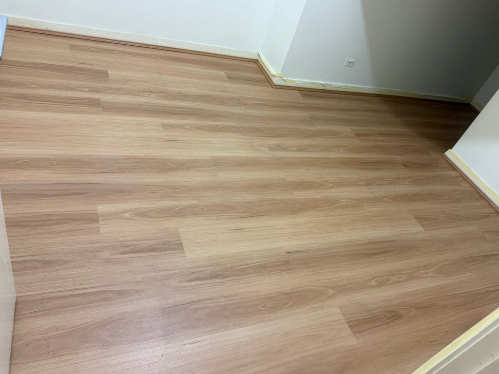 Empty bedroom with a warm light brown timber-look plank floor