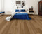 A mid golden brown hybrid plank floor with board variation in a bedroom with a blue bedspread