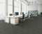 Office floor of dark grey carpet tiles with light grey stripes in a quarter turn pattern