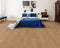 A light to mid warm tan hybrid plank floor with a pinkish beige tone in a bedroom with a blue bedspread