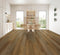 A mid to dark brown hybrid plank floor with strong board variation in a dining room with timber chairs
