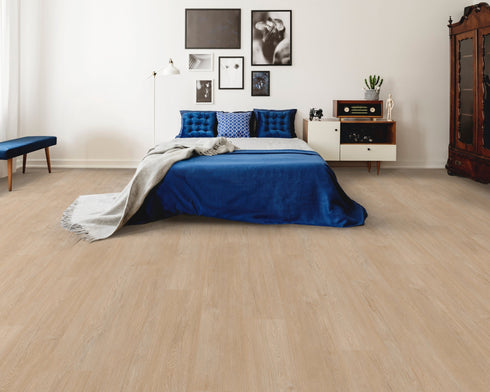 A pale greige hybrid plank floor with a sandy grey tone in a bedroom with a blue bedspread