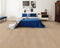 A pale greige hybrid plank floor with a sandy grey tone in a bedroom with a blue bedspread