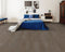 A mid to dark charcoal grey hybrid plank floor in a bedroom with a blue bedspread