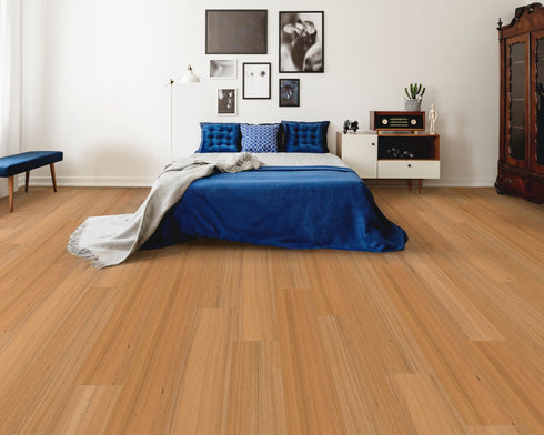 A warm orange-tan hybrid plank floor with a light amber tone in a bedroom with a blue bedspread