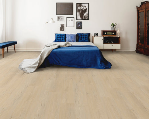 A pale cream beige hybrid plank floor in a bedroom with a blue bedspread